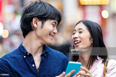 Young Japanese Couple Laughing Watching A Mobile Phone Message High Res
