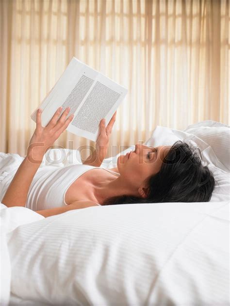 woman reading  book  bed stock image colourbox