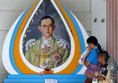 a well wisher gestures in front of a picture of thailand s king bhumibol adulyadej at siriraj