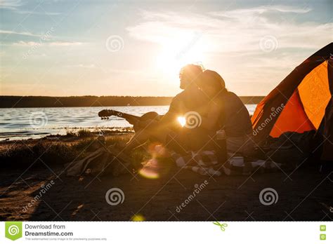 silhouette of couple sitting near touristic tent and hugging stock