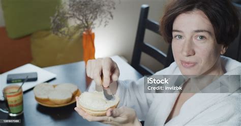 Closeup Portrait Of A Mature Woman Spreading A Toast While Sitting At