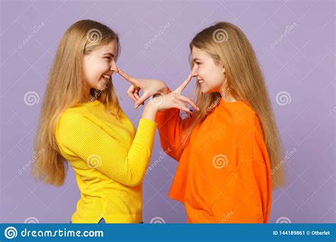 Side View Of Two Funny Blonde Twins Sisters Girls In Colorful Clothes