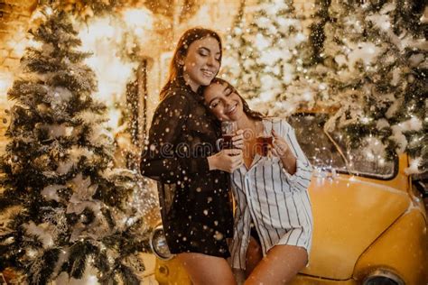 Lesbian Couple Hugs Against Background Of Christmas Decorations And