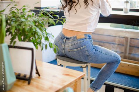 stylish girl in a white t shirt and jeans sits in a cafe on the bar