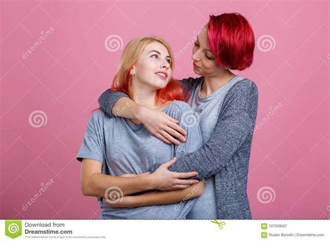 two lesbian girls embrace each other and gaze at each other on a pink
