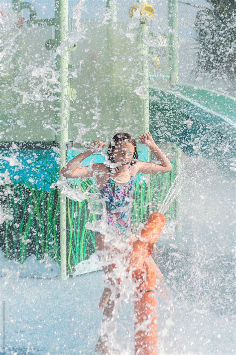 girl at a waterpark being splashed with water under a giant shower by