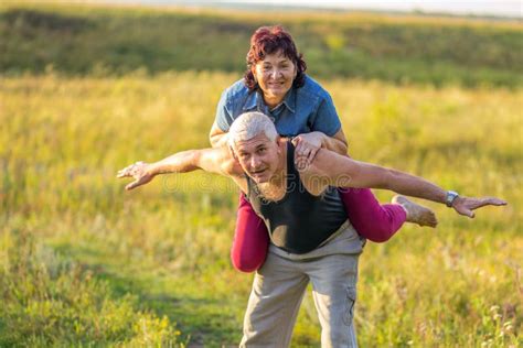 Happy Mature Woman Climbed On Her Husband In The Park Stock Image