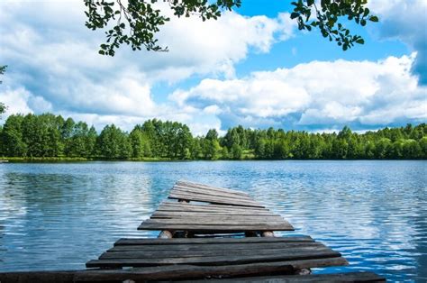 wooden dock sitting  top   lake   blue sky  white clouds