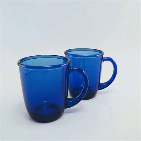 Two Blue Glass Mugs Sitting Next To Each Other