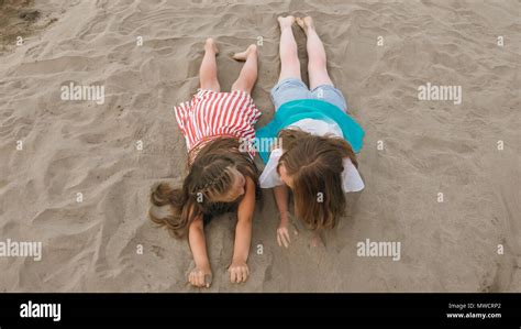 two teenage are lie on a sandy beach near the sea girl playing talk