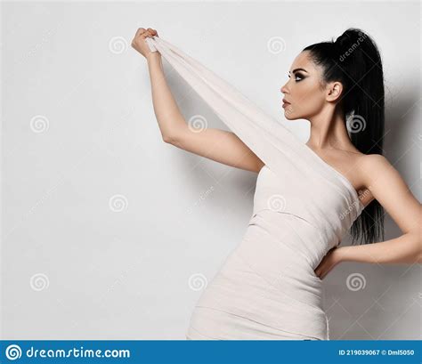 Young Brunette Woman Stands Sideways In White Medical Bandages Body
