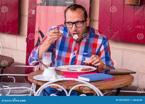 Handsome Young Man Eating Sandwich And Drinking Cappuccino In