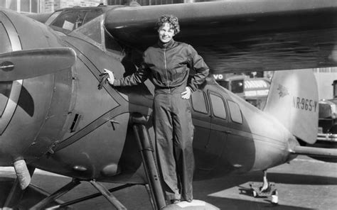 An Old Black And White Photo Of A Woman Standing Next To A Plane