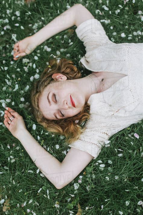 woman lying   blossom covered grass overhead view stock photo