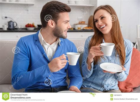 couple in living room talking while sitting on sofa stock