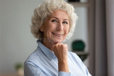 happy older adult grandmother looking at camera posing at home stock