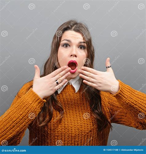 Portrait Of A Amazed Woman With Spread Hands Against Gray Background