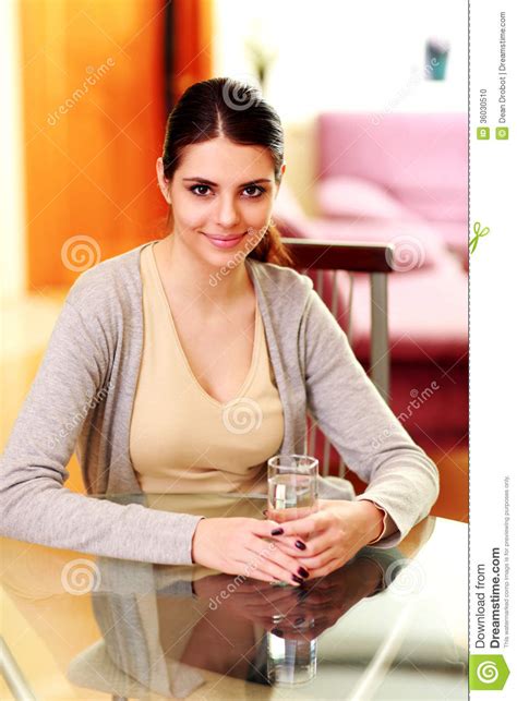 Happy Woman Sitting At The Table And Holding Glass With