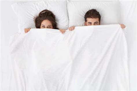 Funny Married Couple Lying In Bed And Hiding Under White