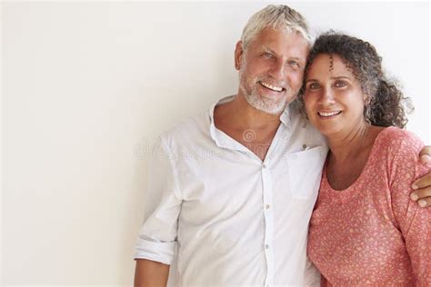 Portrait Of Loving Mature Couple Standing Against Wall Stock Image
