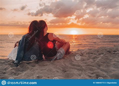 Couple Of Lesbian Girls Sitting On The Beach And Watching And Enjoying