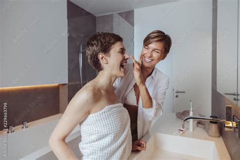 happy lesbian couple getting ready for their day in the bathroom stock
