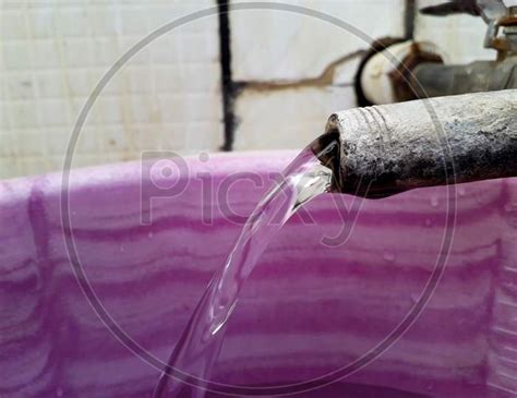 Image Of Water Squirt Or Flow Coming Out From A Tap And Going To Bucket