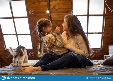 Horizontal Photo Of A Laughing Girl And Her Long Haired Mom Sitting On