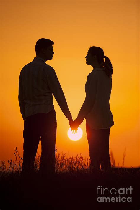 lovers holding hands at sunset in silhouette photograph by lee avison