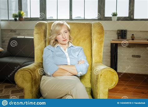 Serious Short Haired Blonde Woman In Blue Shirt Sitting With Crossed