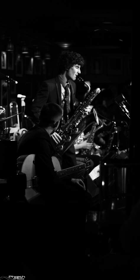 a man in a suit and tie playing music on a saxophone while another man