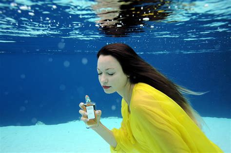 A Woman In A Yellow Dress Holding A Bottle Under Water