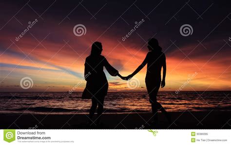 silhouette of two girls holding hands together on beach