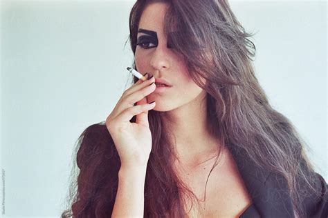 beautiful woman with black eye makeup smoking cigarette by stocksy