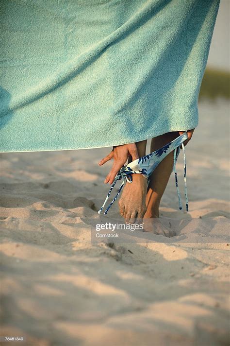 woman removing bathing suit on beach photo getty images