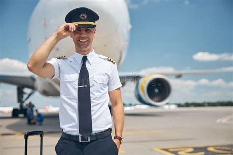 handsome pilot  command standing outdoors  airport stock photo