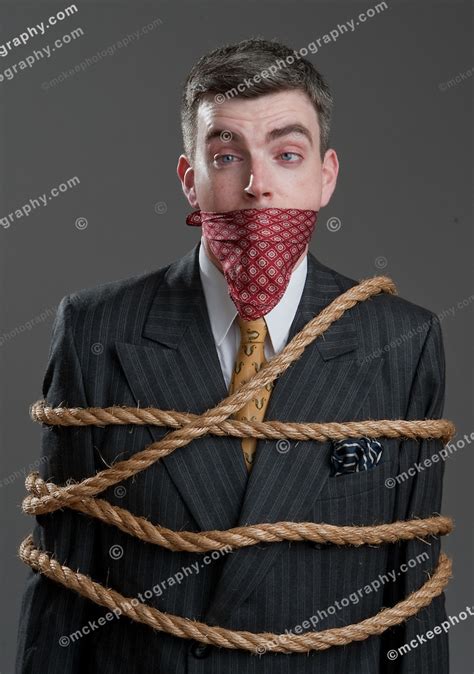 well dressed man in a suit tied up and gagged with a handkerchief
