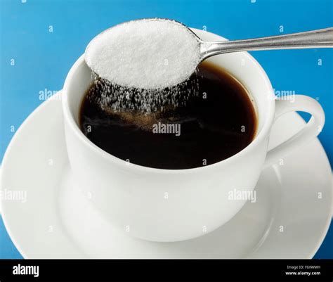 cucharada de azucar  se vierte en la taza de cafe fotografia de stock