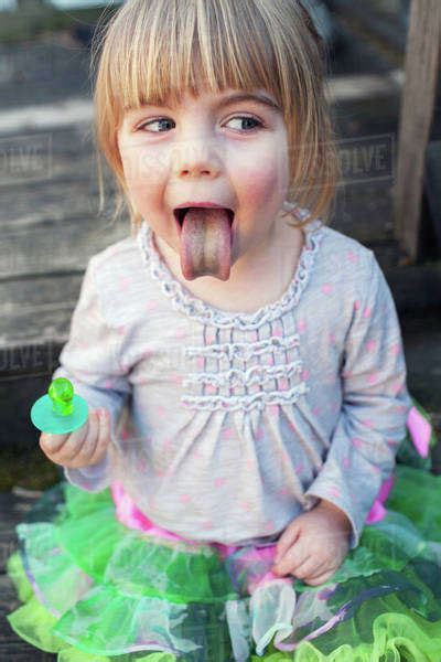 Young Girl Sticking Out Tongue After Sucking On Green Ring Candy