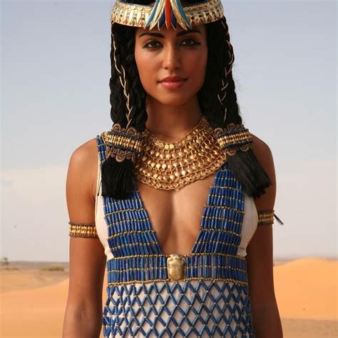 An Egyptian Woman In Blue And White Dress With Gold Jewelry On Her Head