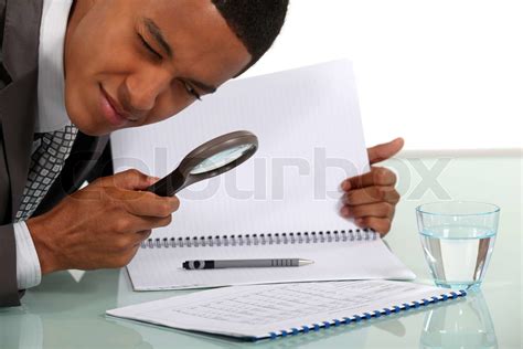 mann ein dokument mit einer lupe untersuchen stock bild colourbox