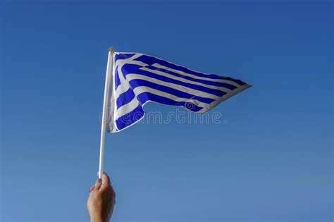 hand waving greek flag in the air for a national