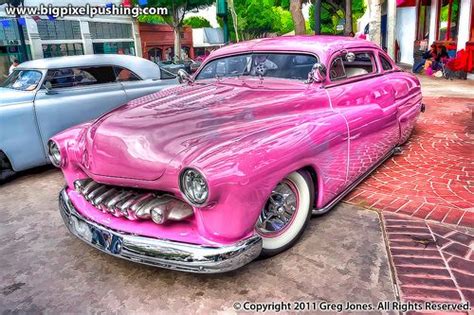 an old pink car parked in front of a building
