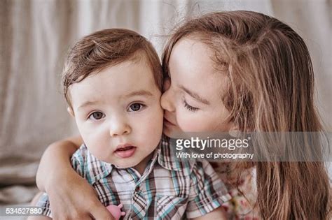 siblings big sister kissing and hugging her little brother photo