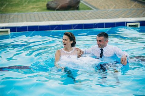 Premium Photo Young Couple Jumping In The Swimming Pool In A Wedding