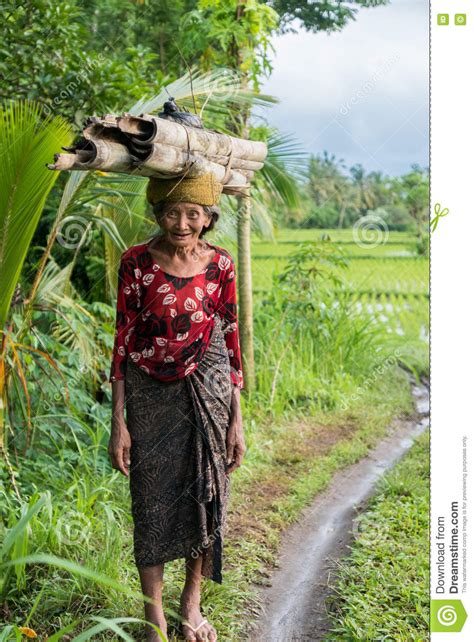 Indonesian Woman Farmer Walking Through The Rice Fields In Ubud Bali
