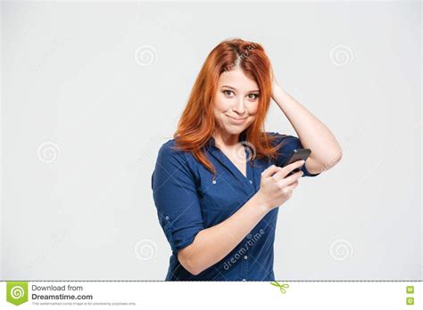 glimlachende mooie roodharige jonge vrouw die smartphone
