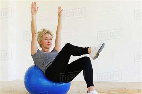 mature woman doing pilates exercise on fitness ball