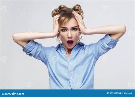 blonde woman screaming with shock holding hands on her head stock