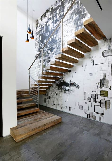 a stair case in front of a wall with pictures on it and lights hanging